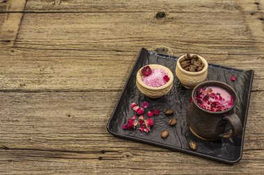 Renkli latte. Gül yaprakları, aromatik şeker, kahve çekirdekleri. Tahta kaplama arka plan