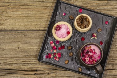 Renkli latte. Gül yaprakları, aromatik şeker, kahve çekirdekleri. Tahta kaplama arka plan