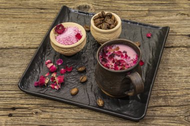 Renkli latte. Gül yaprakları, aromatik şeker, kahve çekirdekleri. Tahta kaplama arka plan