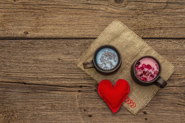 Moon Milk for a better sleep. Rose petals and lavender, felt heart. Valentines Day, romantic concept. Trendy relaxing bedtime drink. Old wooden background