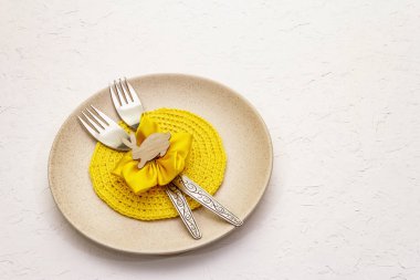 Beyaz macun arkaplanda paskalya masası ayarı. Bahar tatili kartı şablonu. Çatal bıçak, örgü peçete, çiçek.