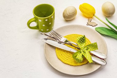 Beyaz macun arkaplanda paskalya masası ayarı. Bahar tatili kartı şablonu. Çatal bıçak, örgü peçete, yumurta, tavşan, lale, puantiye.