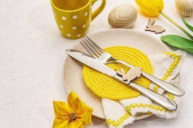 Beyaz macun arkaplanda paskalya masası ayarı. Bahar tatili kartı şablonu. Çatal bıçak, örgü peçete, yumurta, tavşan, lale, puantiye.