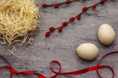 Sıfır atık Paskalya kavramı. Tahta yumurta, kuş yuvası, saten kurdele, kırmızı söğüt fokları. Plastik yok, ekolojik trend. Gri beton arkaplan