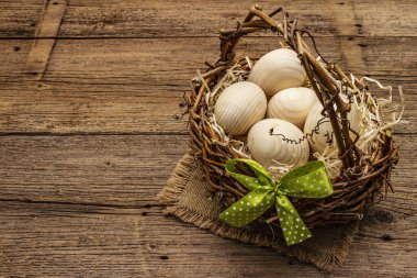 Paskalya hasır sepeti. Sıfır israf, DIY konsepti. Tahta yumurta, talaş, saten fiyonk. Eski tahta arkaplanı, kopyala