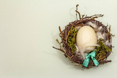 Paskalya kuşu yuvası. Sıfır israf, DIY konsepti. Tahta yumurta, tüy, yosun. Işık arkaplanı, kopyalama alanı, üst görünüm