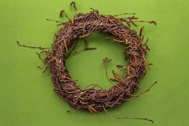 Ağaç dallarının hasır çelengi. Paskalya sıfır atık, DIY konsepti. Tasarım elemanı ve dekor. Yeşil arkaplan, üst görünümü kapat