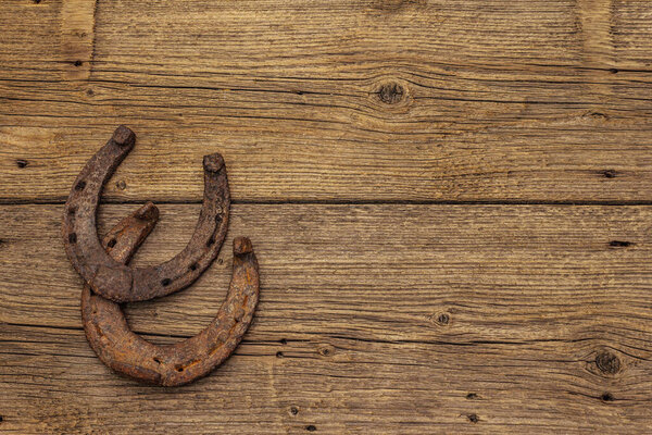 Cast iron metal horse horseshoes. Good luck symbol, St.Patrick's Day concept. Old wooden background, horse accessories, top view