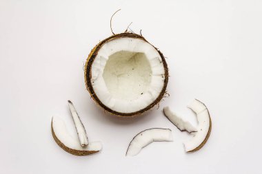Beyaz arka planda yarım yamalak kesilmiş olgun hindistan cevizi. Taze meyve, yemek pişirmek için malzeme veya güzellik için kişisel bakım.