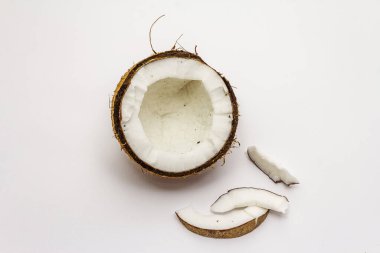 Beyaz arka planda yarım yamalak kesilmiş olgun hindistan cevizi. Taze meyve, yemek pişirmek için malzeme veya güzellik için kişisel bakım.