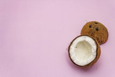 Olgun hindistan cevizi, pembe arka planda yarı izole edilmiş. Taze meyve, yemek pişirmek için malzeme veya güzellik için kişisel bakım.