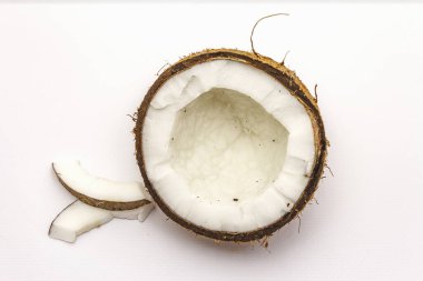 Beyaz arka planda yarım yamalak kesilmiş olgun hindistan cevizi. Taze meyve, yemek pişirmek için malzeme veya güzellik için kişisel bakım.