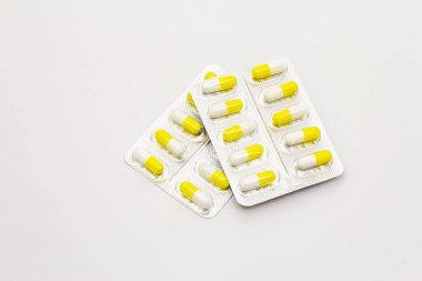 İlaç tabletleri, beyaz arka planda izole edilmiş sarı beyaz kapsüller. Çeşitli hastalıkların tedavisi, geleneksel tıp