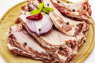 Beyaz arka planda çiğ domuz pirzolası. Yuvarlak tahta kesme tahtası.