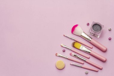 Pembe arka planda makyaj seti. Profesyonel dekoratif kozmetik, güzellik blogcusu konsepti, üst görünüm