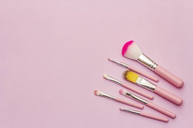 Makyaj fırçaları çeşitliliği. Pembe arka planda kozmetik seti. Profesyonel dekoratif kozmetik, güzellik blogcusu konsepti, üst görünüm