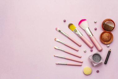 Pembe arka planda makyaj seti. Profesyonel dekoratif kozmetik, güzellik blogcusu konsepti, üst görünüm
