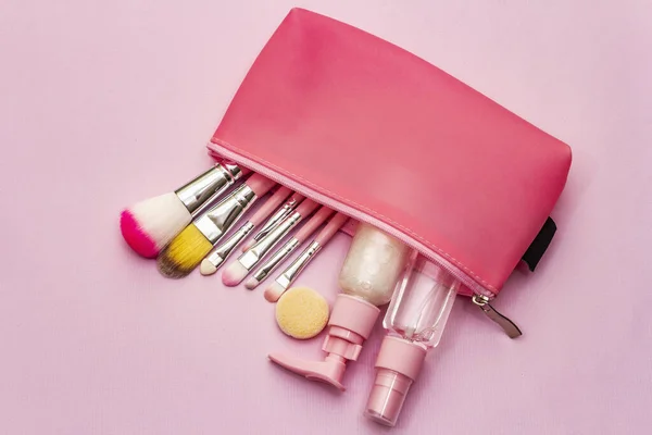 Makeup cosmetic set in bag on pink background. Professional decorative cosmetics, beauty blogger concept, top view
