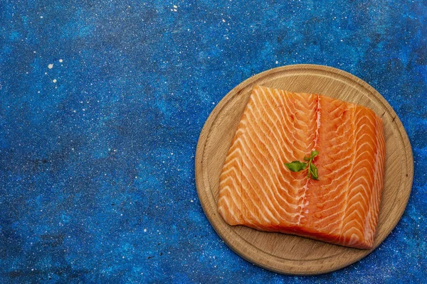 新鮮なサーモンフィレ 木製のまな板 健康でバランスの取れた食事の概念 青い海の背景 トップビュー — ストック写真