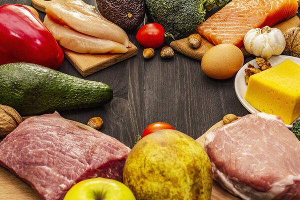 Набор модных кетогенных диетических продуктов. Палео, пиган с низким содержанием углеводов Мясо, рыба, сыр, фрукты и овощи. Чёрные деревянные доски
