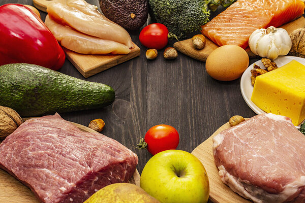 Набор модных кетогенных диетических продуктов. Палео, пиган с низким содержанием углеводов Мясо, рыба, сыр, фрукты и овощи. Чёрные деревянные доски
