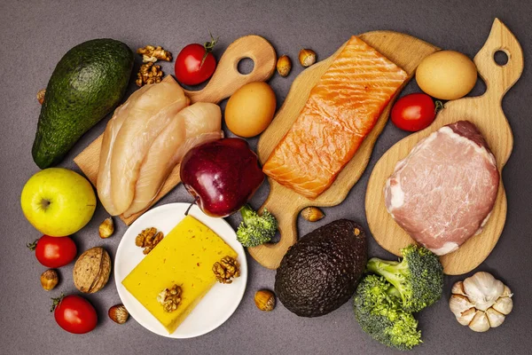 Moda ketojenik diyet ürünleri seti. Paleo, pegan düşük karbonhidrat. Et, balık, peynir, meyve ve sebze. Siyah taş beton arka plan