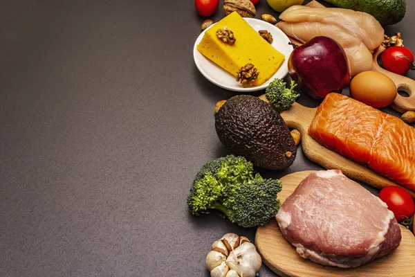 Moda ketojenik diyet ürünleri seti. Paleo, pegan düşük karbonhidrat. Et, balık, peynir, meyve ve sebze. Siyah taş beton arka plan