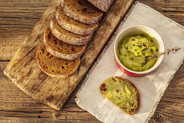 Güneşli sabah kahvaltısı. Sağlıklı yiyecekler, ketojenik diyet konsepti. Taze ekmek, avokado ezmesi, guacamole. Eski tahta arka plan, üst görünüm