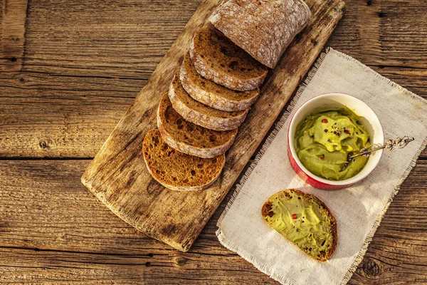 Güneşli sabah kahvaltısı. Sağlıklı yiyecekler, ketojenik diyet konsepti. Taze ekmek, avokado ezmesi, guacamole. Eski tahta arka plan, üst görünüm