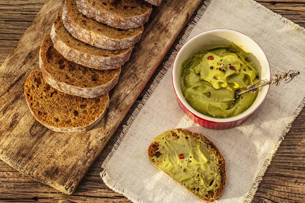 Güneşli sabah kahvaltısı. Sağlıklı yiyecekler, ketojenik diyet konsepti. Taze ekmek, avokado ezmesi, guacamole. Eski tahta arka plan, üst görünüm