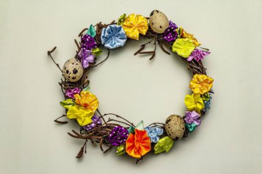 El yapımı Paskalya hasır çelengi, bıldırcın yumurtası ve el yapımı çiçeklerle. Ağaç dalları, benekli saten kurdele. Ev konseptinde kal. Bayramlık Paskalya açık yeşil arka plan, üst görünüm