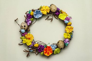 El yapımı Paskalya hasır çelengi, bıldırcın yumurtası ve el yapımı çiçeklerle. Ağaç dalları, benekli saten kurdele. Ev konseptinde kal. Bayramlık Paskalya açık yeşil arka plan, üst görünüm