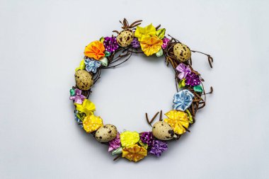 El yapımı Paskalya hasır çelengi, bıldırcın yumurtası ve el yapımı çiçeklerle. Ağaç dalları, benekli saten kurdele. Ev konseptinde kal. Bayramlık Paskalya açık mavi arkaplan, üst görünüm