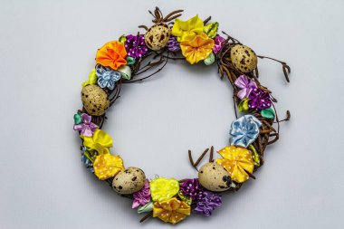 El yapımı Paskalya hasır çelengi, bıldırcın yumurtası ve el yapımı çiçeklerle. Ağaç dalları, benekli saten kurdele. Ev konseptinde kal. Bayramlık Paskalya açık mavi arkaplan, üst görünüm