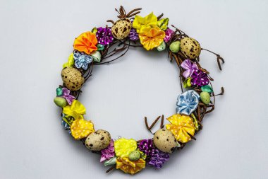 El yapımı Paskalya hasır çelengi, bıldırcın yumurtası ve el yapımı çiçeklerle. Ağaç dalları, benekli saten kurdele. Ev konseptinde kal. Bayramlık Paskalya açık mavi arkaplan, üst görünüm