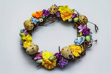 El yapımı Paskalya hasır çelengi, bıldırcın yumurtası ve el yapımı çiçeklerle. Ağaç dalları, benekli saten kurdele. Ev konseptinde kal. Bayramlık Paskalya açık mavi arkaplan