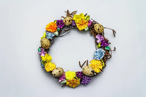 El yapımı Paskalya hasır çelengi, bıldırcın yumurtası ve el yapımı çiçeklerle. Ağaç dalları, benekli saten kurdele. Ev konseptinde kal. Bayramlık Paskalya açık mavi arkaplan, üst görünüm