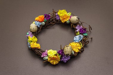 El yapımı Paskalya hasır çelengi, bıldırcın yumurtası ve el yapımı çiçeklerle. Ağaç dalları, benekli saten kurdele. Ev konseptinde kal. Bayramlık Paskalya siyah arkaplanı, üst görünüm