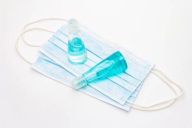 Maske ve dezenfektan beyaz arka planda izole edilmiş. Kişisel hijyen ve viral hastalıkların önlenmesi için tıbbi ürünler. Coronavirus, COVID-19 salgını, 2019-NCoV dünya çapında kavram