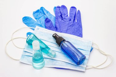 Maske, eldiven, dezenfektan beyaz arka planda. Kişisel hijyen ve viral hastalıkların önlenmesi için tıbbi ürünler. Coronavirus, COVID-19 salgını, 2019-NCoV dünya çapında kavram