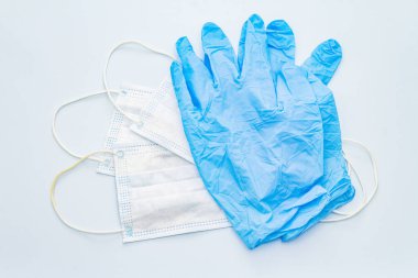 Maske ve eldivenler mavi arka planda izole edilmiş. Kişisel hijyen ve viral hastalıkların önlenmesi için tıbbi ürünler. Coronavirus, COVID-19 salgını, 2019-NCoV dünya çapında kavram