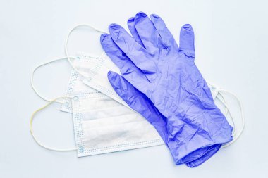 Maske ve eldivenler mavi arka planda izole edilmiş. Kişisel hijyen ve viral hastalıkların önlenmesi için tıbbi ürünler. Coronavirus, COVID-19 salgını, 2019-NCoV dünya çapında kavram