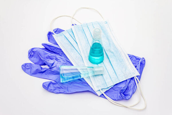 Маска, перчатки, дезинфицирующее средство на белом фоне. Медицинские препараты для личной гигиены и профилактики вирусных заболеваний. Коронавирус, пандемический COVID-19, всемирная концепция 2019-nCoV
