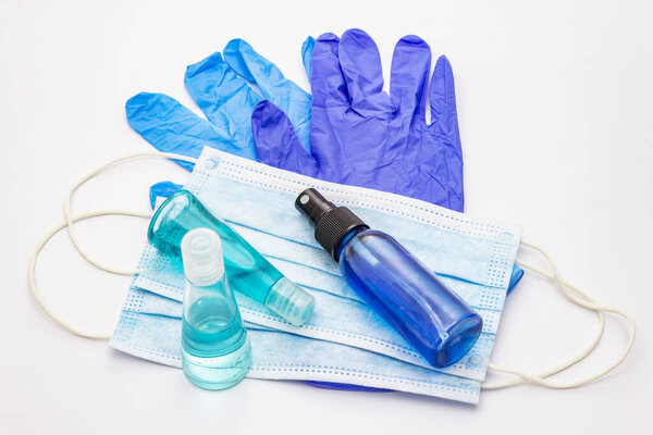Маска, перчатки, дезинфицирующее средство на белом фоне. Медицинские препараты для личной гигиены и профилактики вирусных заболеваний. Коронавирус, пандемический COVID-19, всемирная концепция 2019-nCoV

