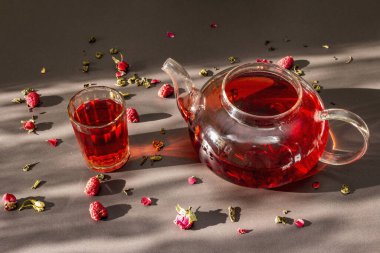 Güneşli sabah kahvaltısı. Kuru meyve, çiçek ve yapraklı çaydanlık içinde ahududu yeşili çay. Moda siyah taş arkaplan