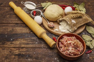 Hamur köftesi, ravioli, lezzetli turtalar ve kiş hazırlamak için taze ham malzemeler. Dolma, un, hamur, yumurta, baharat. Klasik ahşap masa arkaplanı