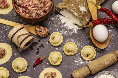 Çiğ hamur köfteleri ve modaya uygun siyah beton arka plan malzemeleriyle kompozisyon. Yemek pişirme süreci, taze ürünler.