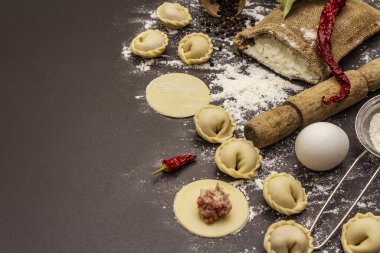 Çiğ hamur köfteleri ve modaya uygun siyah beton arka plan malzemeleriyle kompozisyon. Yemek pişirme süreci, taze ürünler.