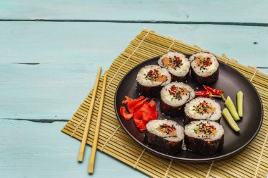Kore usulü Gimbap (kimbob). Buğulanmış beyaz pirinç (bap) ve diğer malzemeler. Moda turkuaz ahşap tahta arka plan