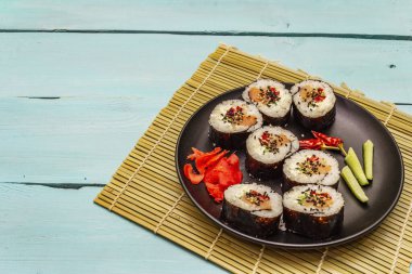Kore usulü Gimbap (kimbob). Buğulanmış beyaz pirinç (bap) ve diğer malzemeler. Moda turkuaz ahşap tahta arka plan